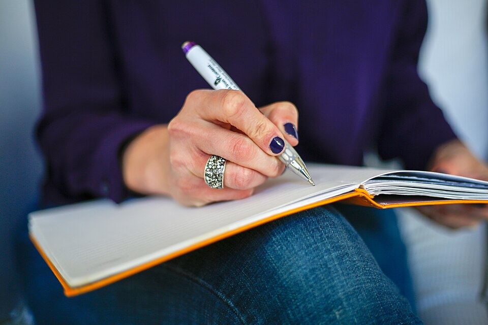 A hand writing in an open notebook