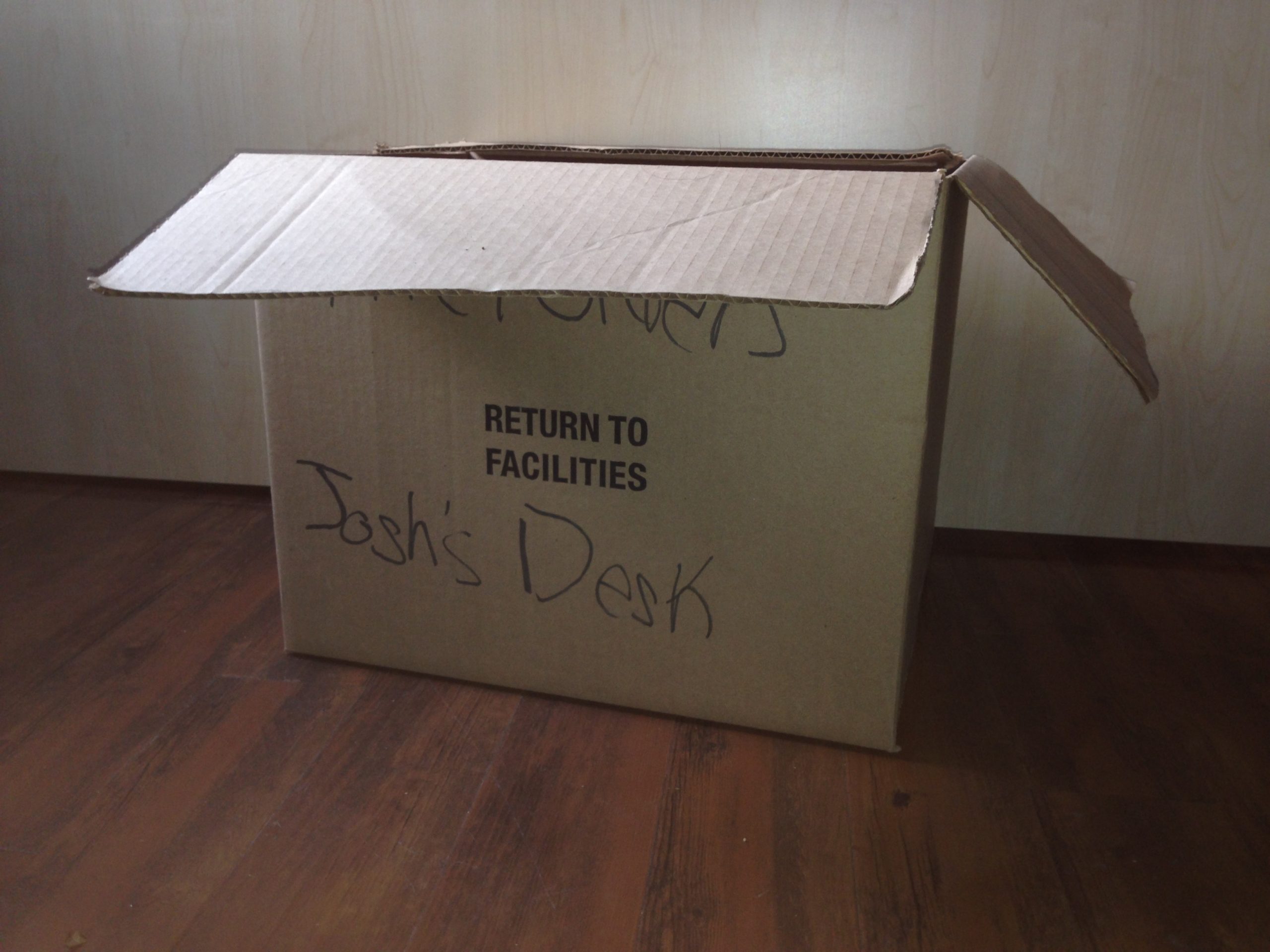 A cardboard box marked Return to Facilities with a name written on the side